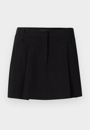 Musta läppäröity hame, joka on valmistettu sileästä kankaasta. Hameessa on vyötärönauha ja etutaskut, sekä suora, taipuva siluetti.