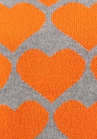 Strickstoffmuster mit großen orangen Herzen auf grauem Hintergrund, das die detaillierte Textur des Garns zeigt.
