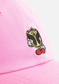 Roze pet met corduroy textuur, voorzien van een geborduurd cartoonfiguur dat een geel schild vasthoudt, gedetailleerd met zwarte omtrekken en rode accenten.