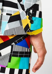 Colorful geometric-patterned suit featuring vibrant shades of blue, red, yellow, and green, with four black button accents on the sleeve.