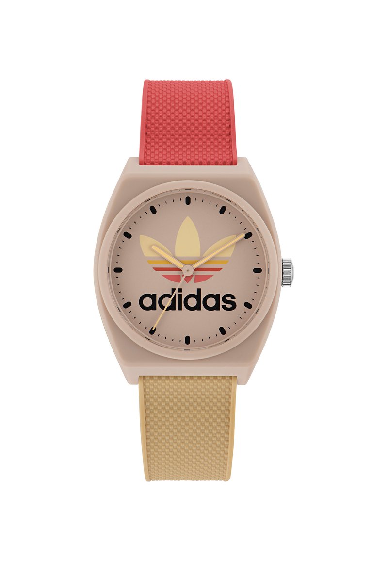 Adidas-klocka med ett beige plastkapsel, rosa och gula randade urtavla, svart logotyp och texturerade röda och gula silikonarmband.