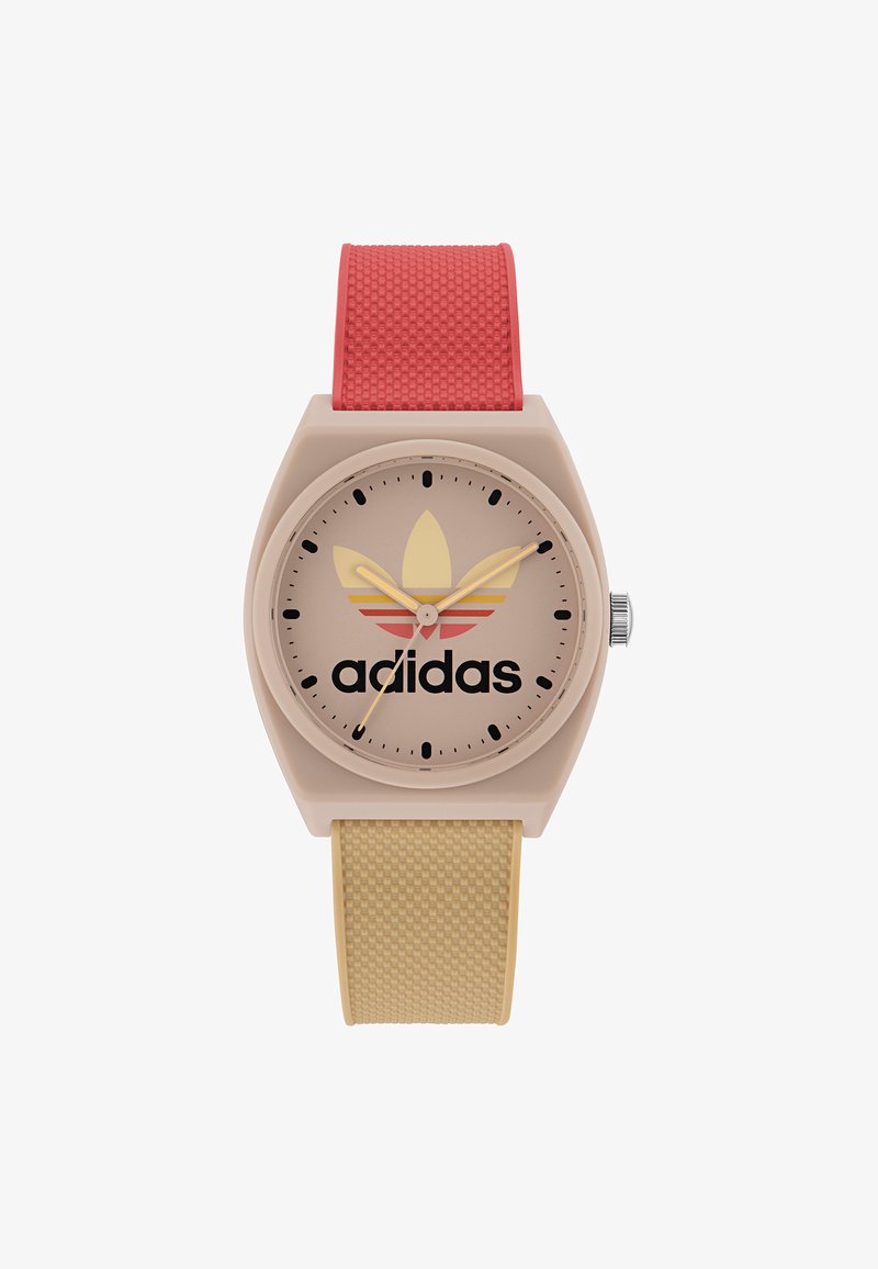Adidas-klocka med ett beige plastkapsel, rosa och gula randade urtavla, svart logotyp och texturerade röda och gula silikonarmband.
