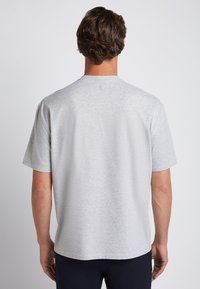 Grijze korte mouwen t-shirt van zachte stof, met een ronde halslijn en een klein logo-details nabij de kraag op de achterkant.