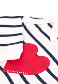 Ριγωτό ύφασμα σε λευκό και ναυτικό μπλε με μεγάλο κόκκινο καρδιά γραφικό. Λογότυπο "Petit Bateau" σε λευκό κοντά στο κάτω μέρος. Απαλό βαμβακερό υλικό.