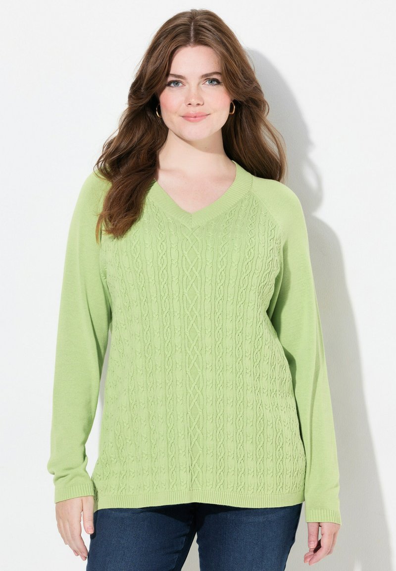 Vaaleanvihreä neulottu villapaita, jossa on V-pääntie, jalokivikaulustyylinen kuviointi ja pitkät hihat. Yhdistetty tummansinisiin farkkuihin.