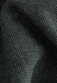 Tissu texturé de couleur gris foncé présentant un petit motif à carreaux. Le matériau semble doux, avec une structure de surface finement tissée.