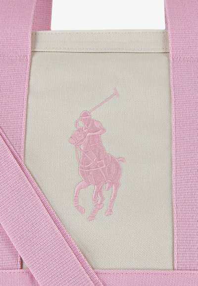 Béžová bavlnená taška s ružovými ušami a vyvýšeným ružovým logom pólistu. Dizajn obsahuje textil s textúrou a zosilneným šitím.