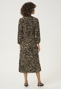 Haljina s uzorkom leoparda, tri četvrtine rukava, s cinčanim strukom i dužinom do koljena. Tkanina je lagana s glatkom teksturom. Crni naglasci.