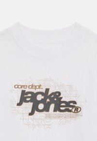 Hvit bomulls t-skjorte med rund hals, med et trykt design i brunt og svart som leser "core dept. jack & jones" og abstrakte linjer.