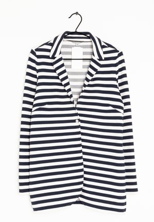 Blazer rayé bleu marine et blanc avec col à revers et un bouton, suspendu sur un cintre noir avec des étiquettes de prix attachées.