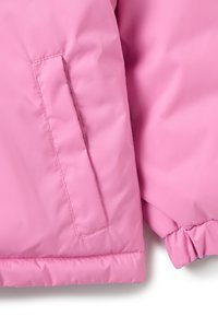 Giacca isolante rosa con una superficie liscia e lucida, polsini elasticizzati e una tasca laterale con cucitura nascosta per un aspetto pulito.