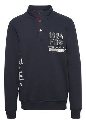 Jūras spēku džemperis ar augstu apkakli, ar pogu klāstu, izšūtām dizaina detaļām un kontrastējošiem sarkaniem akcentiem. Mīksta auduma ar ribotām piedurknēm.