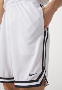 Pantalones cortos deportivos blancos hechos de tela de malla, con rayas laterales negras y un pequeño logo negro en la parte delantera, con una cinturilla elástica.
