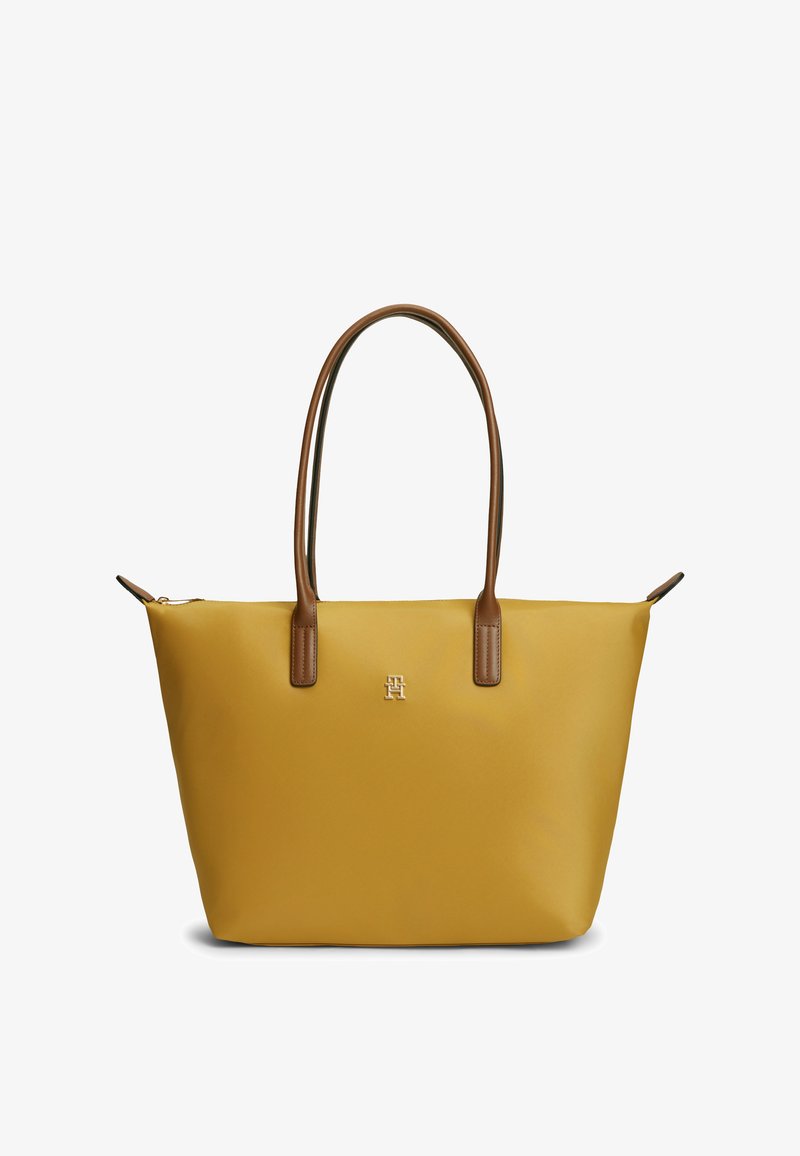 Sac fourre-tout jaune avec des poignées en cuir marron et un petit logo métallique centré près du haut, présenté sur un fond blanc.