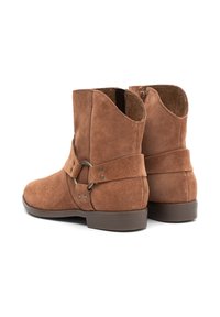 Botas de ante marrón hasta el tobillo con punta redondeada, cierre de cremallera lateral y una correa decorativa alrededor del tobillo con acentos metálicos.