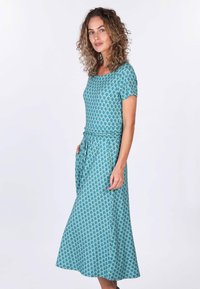 Türkisfarbenes Kleid mit einem Kurzarmdesign, das ein sich wiederholendes Blattmuster aufweist. Es hat eine taillierte Passform und Taschen und besteht aus einem glatten Stoff.