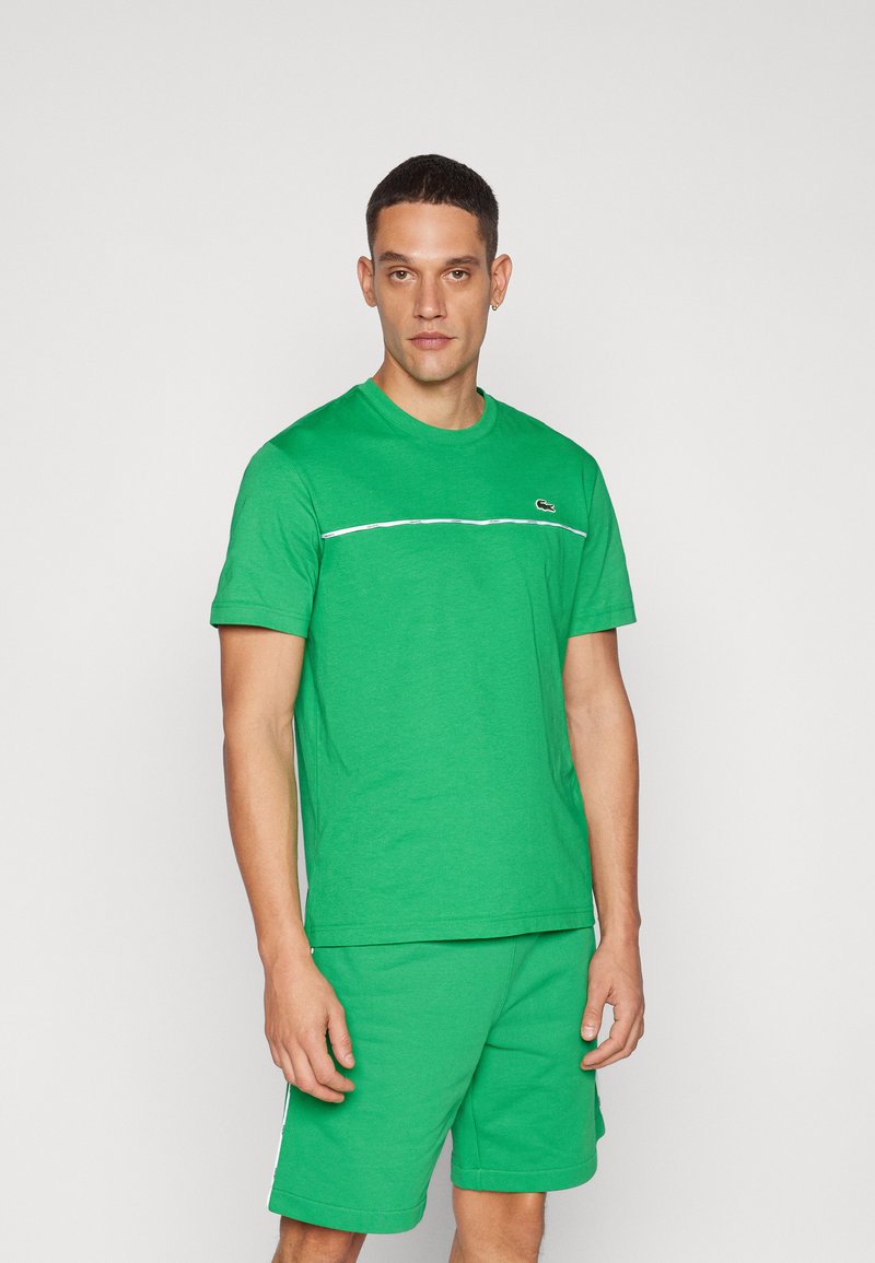 Groene katoenen T-shirt met korte mouwen en een ronde hals, met een horizontale witte streep over de borst en een klein logo.