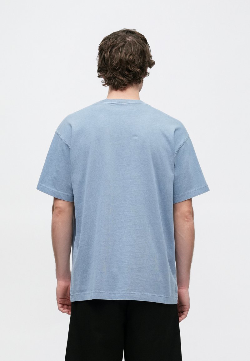 T-shirt en coton bleu à coupe décontractée, manches courtes et col rond. Présente des détails de couture subtils et une texture lisse.