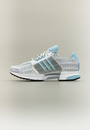 Baskets athlétiques blanches et bleu clair avec empeigne en mesh, supports latéraux en plastique, lacets et semelle rembourrée, vues de profil sur fond neutre.