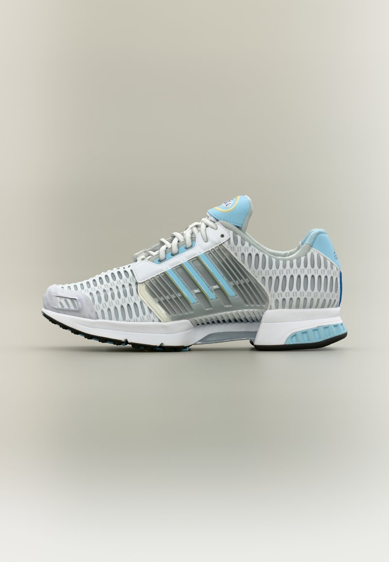 Λευκό και ανοικτό μπλε αθλητικό παπούτσι με επάνω μέρος από δίχτυ, πλαστικές πλευρικές στηρίξεις, κορδόνια και μαλακή σόλα, εμφανιζόμενο από το πλάι σε ουδέτερο φόντο.