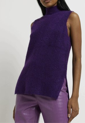 Ærmeløs lilla strikket rullekravesweater kombineret med højttaljede lilla bukser i imiteret læder med krokodilletekstur.