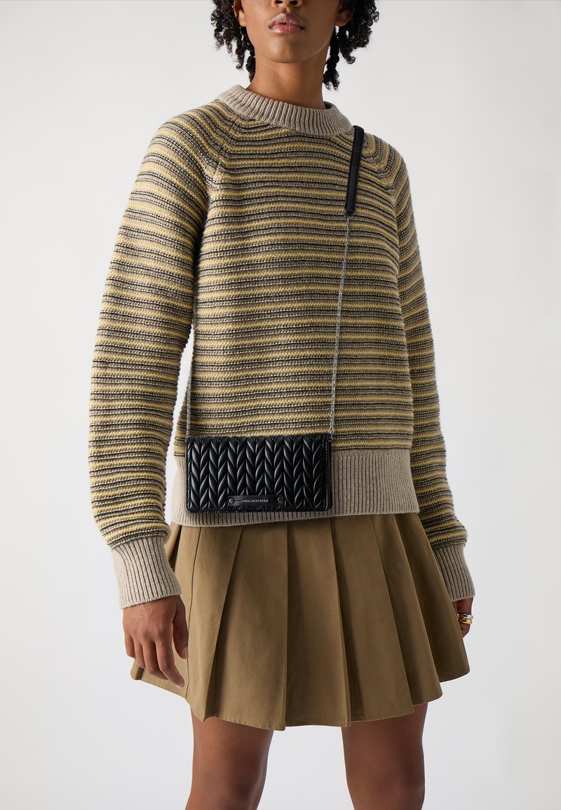 Maglione a righe in beige e oliva con scollatura a coste. Abbinato a una gonna plissettata oliva, con una borsa a tracolla nera texturizzata.