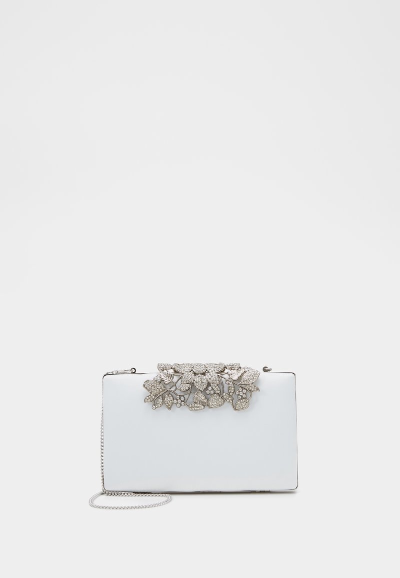 Pochette rectangulaire blanche avec un ornement floral métallique recouvert de strass. Dispose d'une chaîne en argent pour le porté.