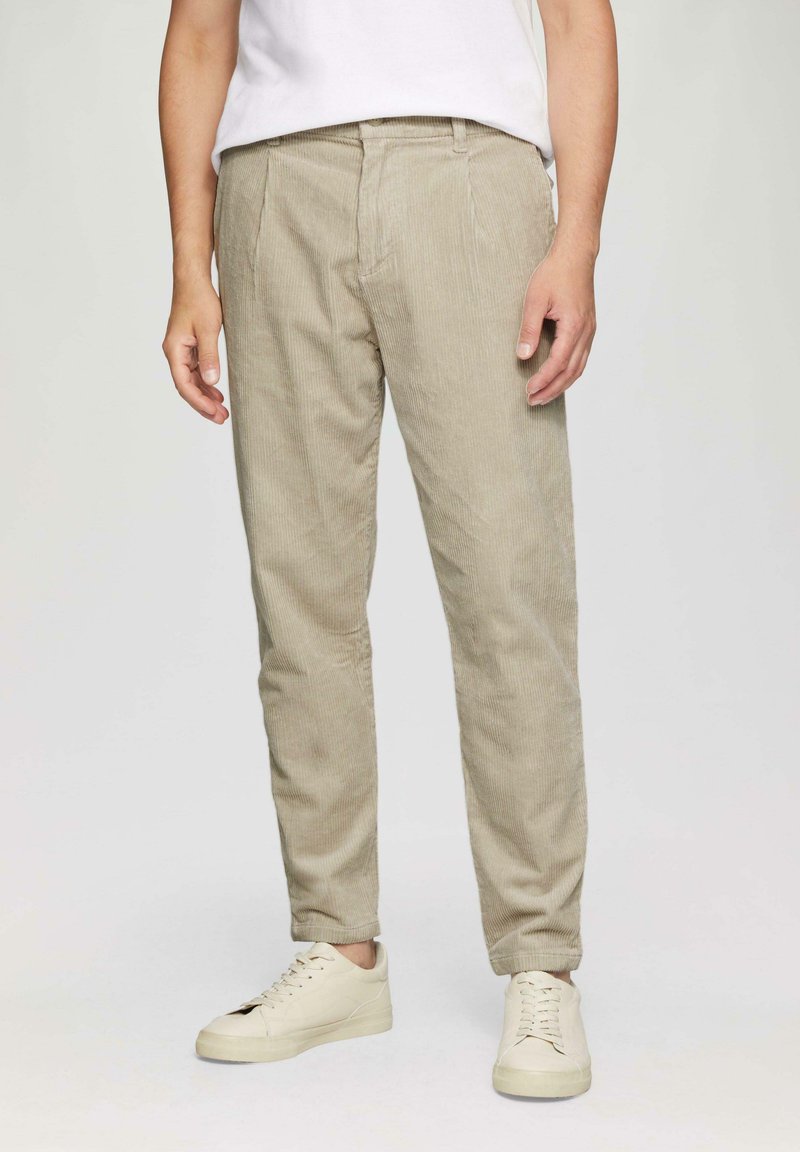 Beige corduroybroek met een slim fit, voorzien van zijzakken en een gladde textuur, gecombineerd met lichtgekleurde sneakers.