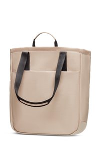 Sac fourre-tout beige en tissu lisse, avec des poignées noires et une poche avant. Design carré avec des coins inférieurs renforcés.