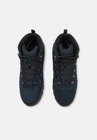 Botas de senderismo en azul marino con parte superior de ante y malla, suela de goma, ojales de metal y sistema de cordones; cuello acolchado para mayor comodidad.