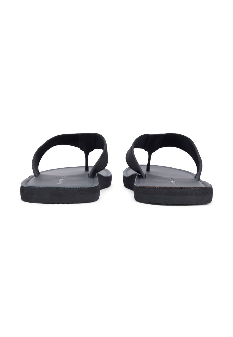 Ζευγάρι μαύρα σανδάλια τύπου σαγιονάρα με επίπεδες σόλες, φαινομενικά από πίσω που δείχνουν τα λουράκια και τις υφασμένες σόλες.