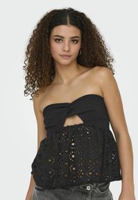 Top nero senza spalline con corpetto testurizzato, dettaglio frontale a torsione e sezione con ritaglio. Il peplum inferiore presenta un design floreale ad occhio di pernice.