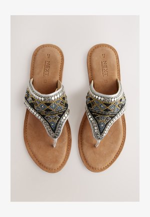 Karoliukais dekoruotos tanga tipo basutės su pilkai mėlynu raštu, pabarstytos sidabro ir aukso akcentais, pastatytos ant rusvos dirbtinio zomšos pado.