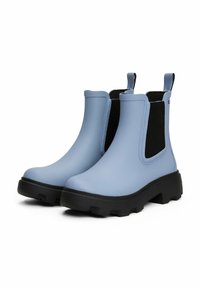 Bottes en caoutchouc bleu clair jusqu'à la cheville avec des panneaux élastiques noirs, des semelles texturées et des languettes ; présentent un design épais et un matériau imperméable.