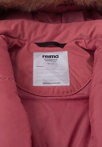 Giacca impermeabile rosa per bambini Reima con interno che mostra un rivestimento in morbido tessuto, un'etichetta di cura e un'area del cappuccio rifinita con pelliccia.