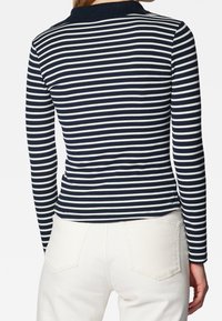 Námořnický a bílý pruhovaný svetr s dlouhým rukávem a límečkem; vroubkovaná textura, přiléhavý design a postranní rozparky na spodním lemu. Nosit s bílými kalhotami.