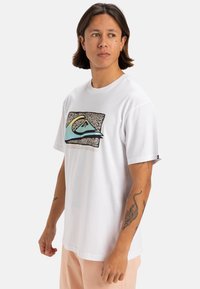 Camiseta blanca de manga corta con un diseño gráfico colorido de olas y una montaña. Hecha de algodón suave con un corte relajado.