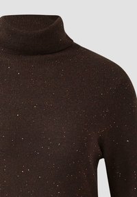 Maglione a collo alto marrone scuro con una texture a coste, caratterizzato da punteggiature metalliche sparse per un tocco di dettaglio. Primo piano del collo e del tessuto.