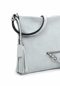 Lysegrå læderhåndtaske med sortkantet håndtag, forreste lynlåslomme og dekorativ kvast fastgjort til remmen.