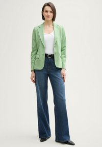 Sacou verde deschis cu două butoane, asortat cu blugi din denim închis, cu talie înaltă și croială largă. Top alb dedesubt, curea neagră și pantofi cu vârf ascuțit.