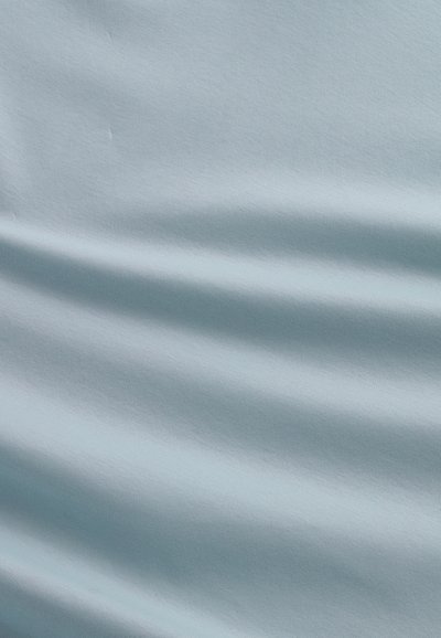 Ljusblått tyg med en slät textur, som har subtila veck och variationer i nyansen. Inga synliga mönster eller accenter.