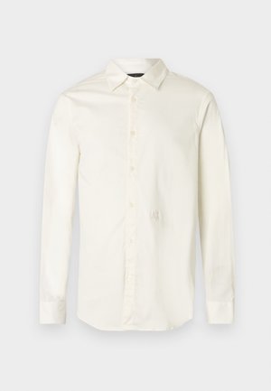 Langärmliges weißes Hemd aus Baumwolle. Mit spitzem Kragen, durchgeknöpftem Vorderteil und dezentem Logo, das auf der Brust gestickt ist.
