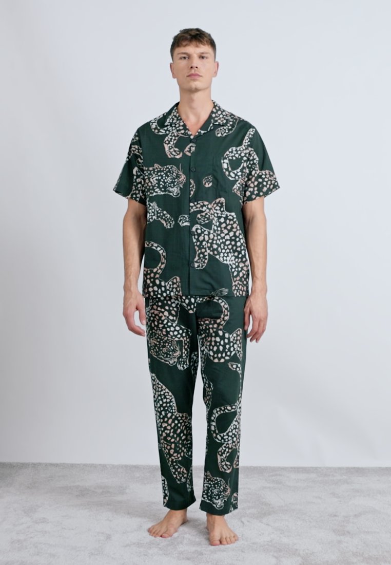 Ensemble de pyjama à motif vert comprenant une chemise à boutons à manches courtes et un pantalon long avec des motifs d'animaux et des détails clairs contrastants.