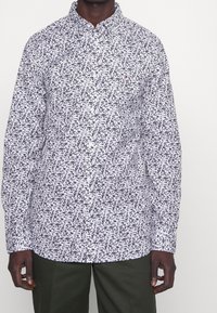 Pitkähihaine nappikauluspaita valkoisena, jossa on abstrakti musta ja harmaa kukkakuosi. Ominaisuuksiin kuuluu kauluspaita ja normaali istuvuus.