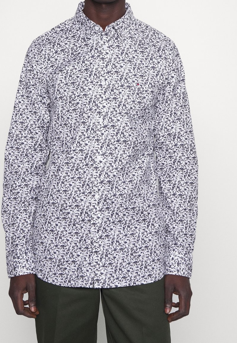 Pitkähihaine nappikauluspaita valkoisena, jossa on abstrakti musta ja harmaa kukkakuosi. Ominaisuuksiin kuuluu kauluspaita ja normaali istuvuus.