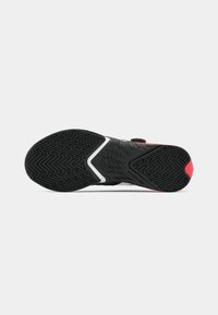 Black athletic shoe sole with a textured rubber surface, featuring a red accent and a white stripe. Designed for traction and stability.