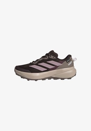 Czarno-beżowy but do biegania trailowego Adidas Terrex z różowymi paskami i grubą podeszwą, zaprojektowany do użytku na świeżym powietrzu.