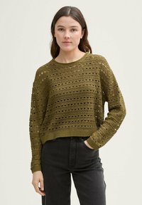 Olijfgroen cropped gebreid sweater met openwork patronen, ronde hals en lange mouwen; gecombineerd met donkere jeans.