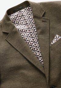Blazer marrón texturizado con solapas de pico, que presenta un forro interior estampado en blanco y marrón, y un pañuelo de bolsillo a juego.