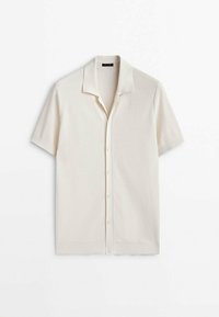 Chemise en maille beige à manches courtes, avec un col doux, des boutons espacés régulièrement et un motif texturé subtil.